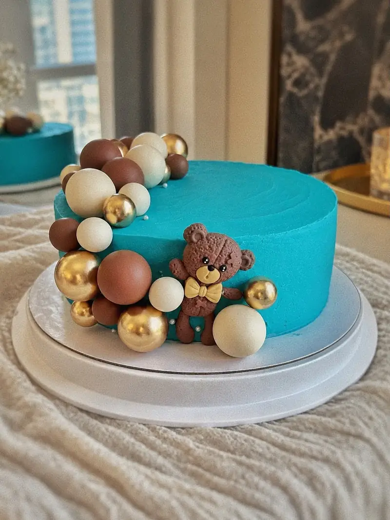 Torta con ganache turquesa, esferas de chocolate y doradas y un osito para un cumpleaños infantil