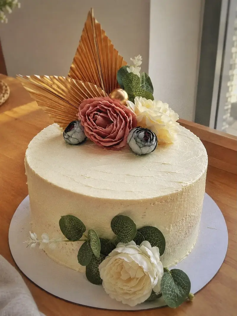 White buttercream cake with gold palm leaves and roses